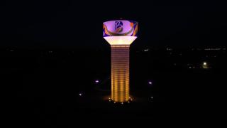 The Bondurant Water Tower lit up at night with Vermeer-branded color scheme