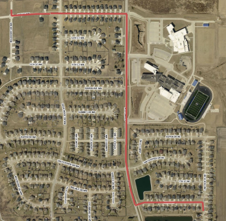 Aerial map of a residential neighborhood with a red line marking a house-moving route.